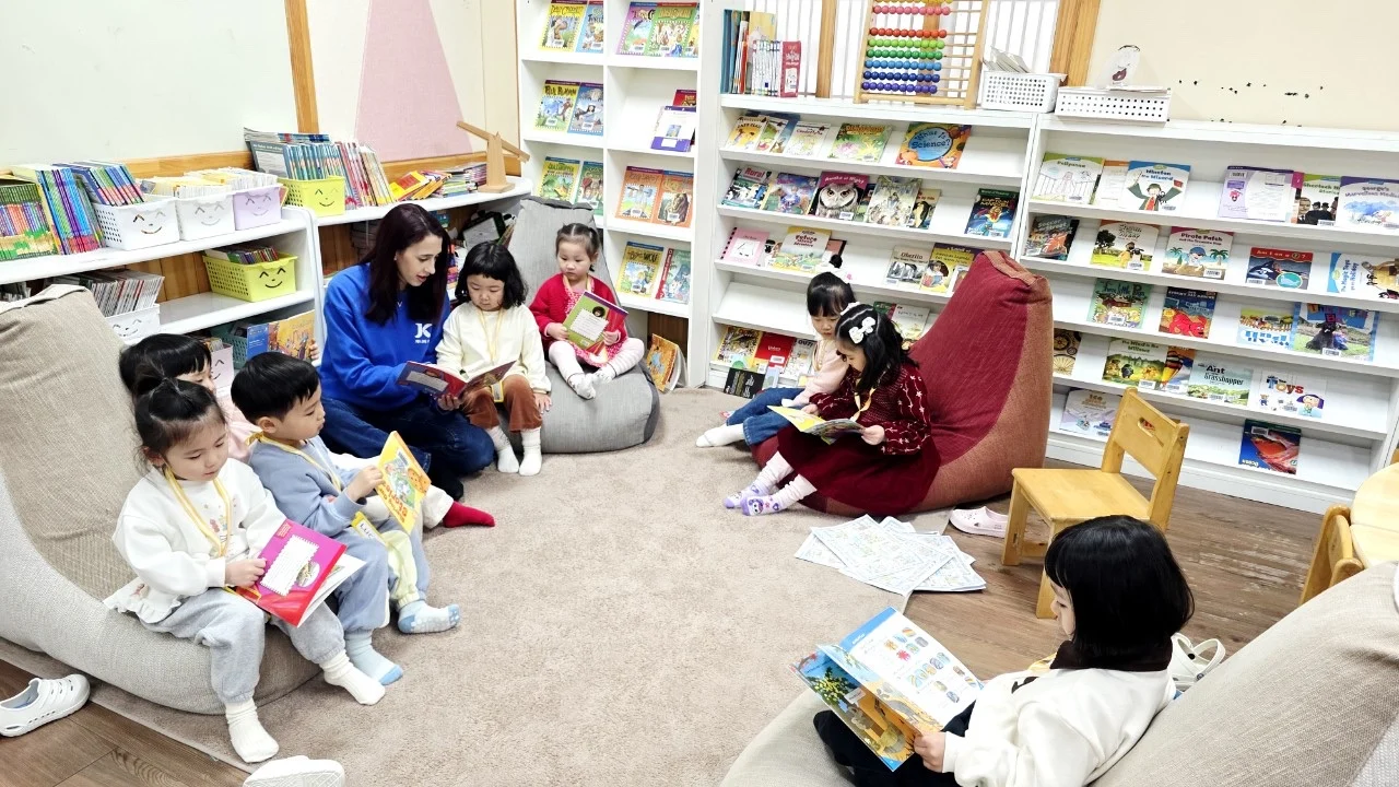 선생님과 아이들이 도서 공간에서 함께 책을 읽는 모습