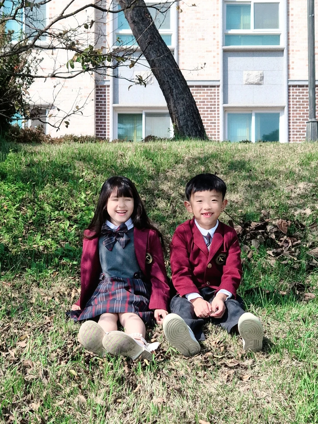 잔디 위에 나란히 앉아 환하게 웃는 제니퍼키즈 아이들